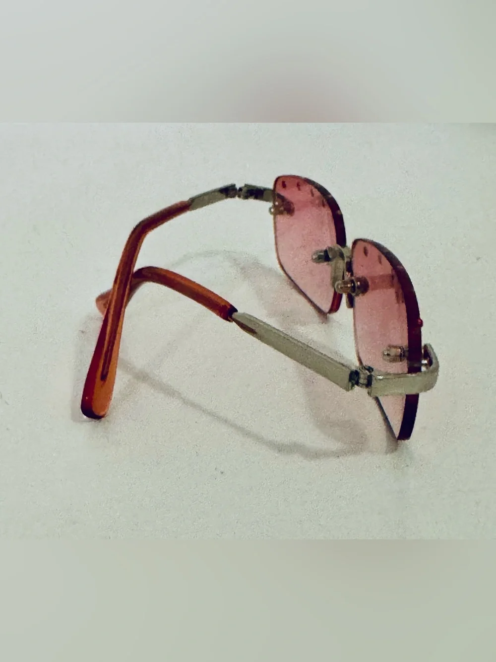 Stylish pink rimless sunglasses adorned with decorative rhinestones. These glass